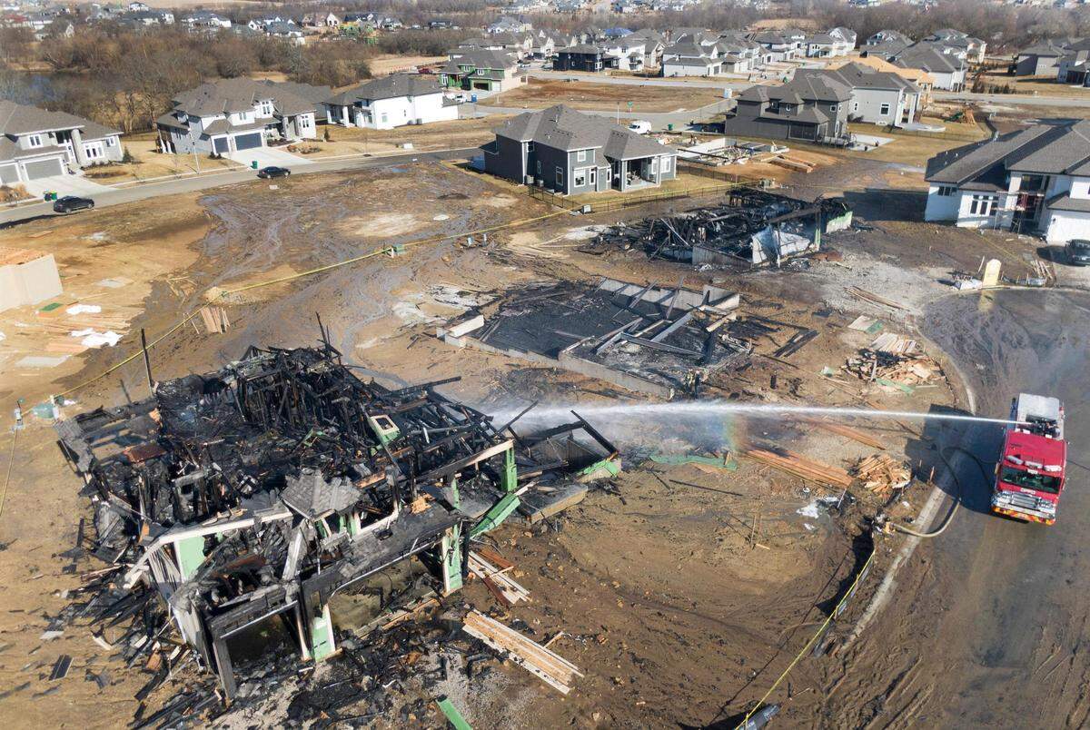A crew from the Overland Park Fire Department sprayed water on the smoldering remains of one of three large houses under construction that caught fire and burned down early Monday, Feb. 28, 2022, in the Stone Creek of Terrybrook Farms subdivision at 11100 W. 172nd Terrace in Overland Park. There were no injuries in the fire.