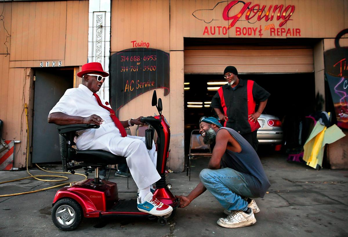 Kae Chris checks damage to the scooter of Robert Wallace, 85, as he stops by Young Auto Repair in the 3100 block of North Grand Boulevard on Wednesday, Oct. 7, 2020. The shop, which opened in 1977, is sandwiched between Bing Lau Chop Suey and and the former Bad Habitz Social Club, where shootings outside both businesses this year have left three men dead and four wounded. “We can’t even conduct business in a normal way without being worried about people carrying guns,” said Chris.