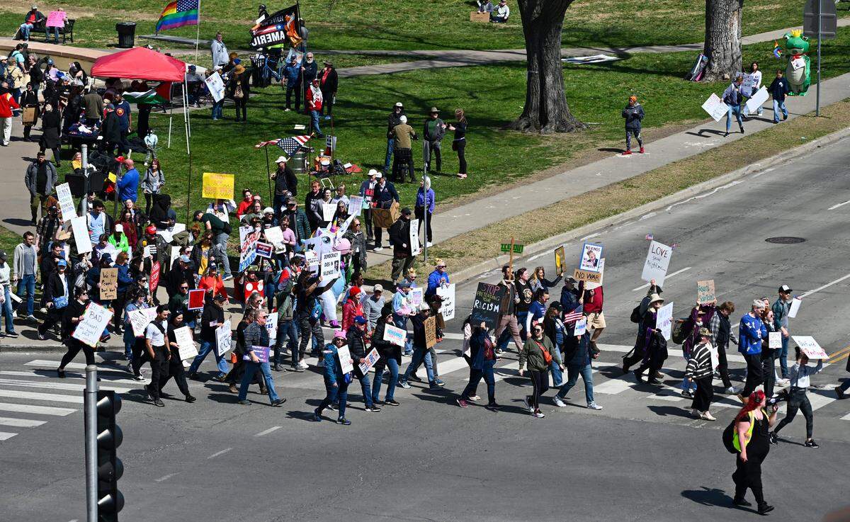 Protesters crossed a sidewalk near the Country Club Plaza on Saturday, March 28, 2026, during a No Kings protest against the Trump administration in Kansas City.
