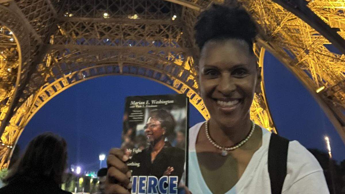 Former KU great Lynette Woodard, while in Paris for the 2024 Olympics, holds a copy of her college coach Marian Washington’s new book, “FIERCE: My Fight for Nothing Less.”