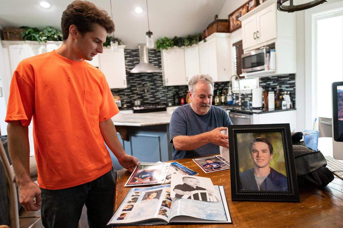 At their home in Kansas City, Trey and Robert Keating go through photos of Kyle Keating, brother to Trey and son to Robert, on Saturday, July 2, 2022. Kyle, a motorcyclist, died as a result of an accident with a RideKC bus in March.