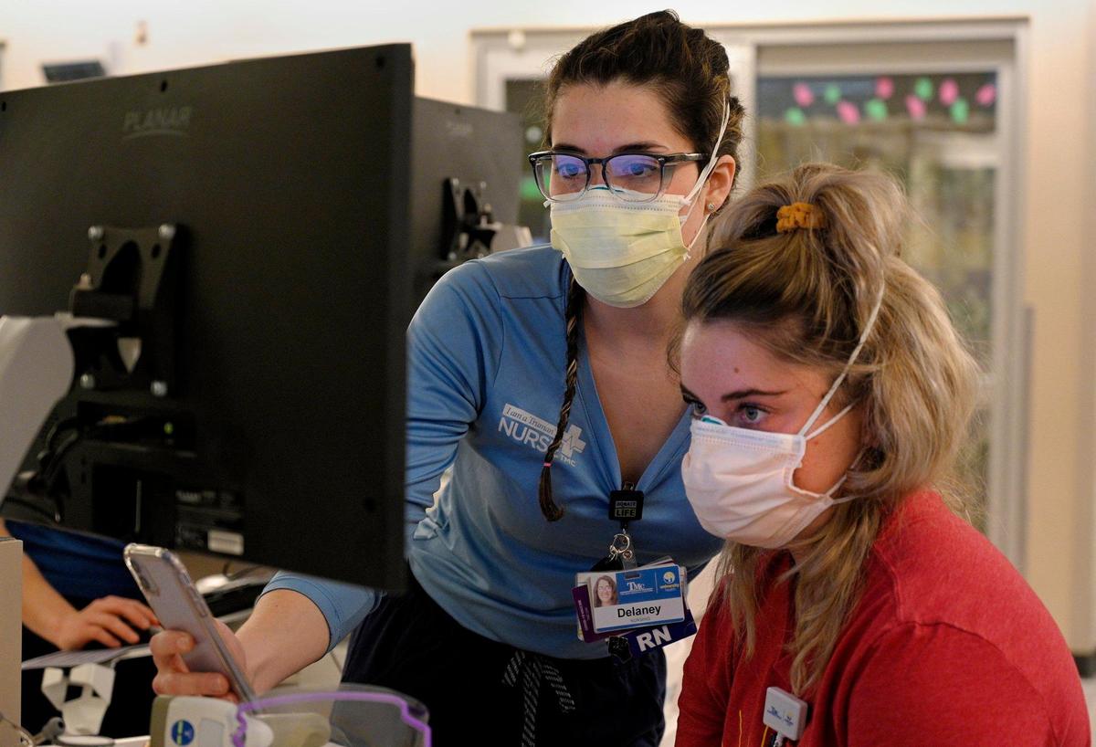In the COVID intensive care unit at University Health, Delaney Swanson, left, a registered nurse, shows Andi Piper, a nurse resident, the charting process.