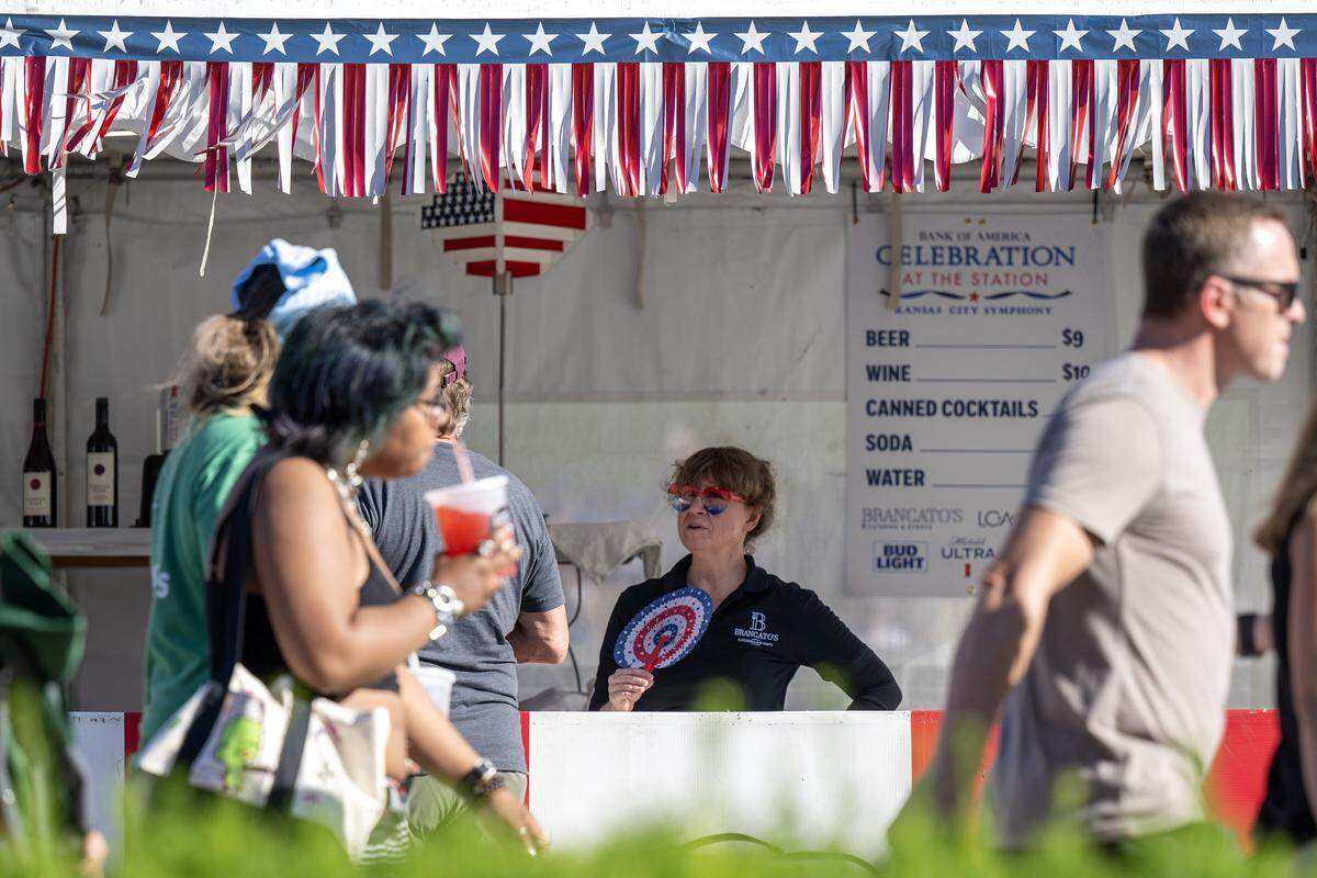 A volunteer wearing heart-shaped sunglasses stands inside a concession tent during the Kansas City Symphony's annual Celebration at the Station concert at Union Station on Sunday, May 24, 2026, in Kansas City.