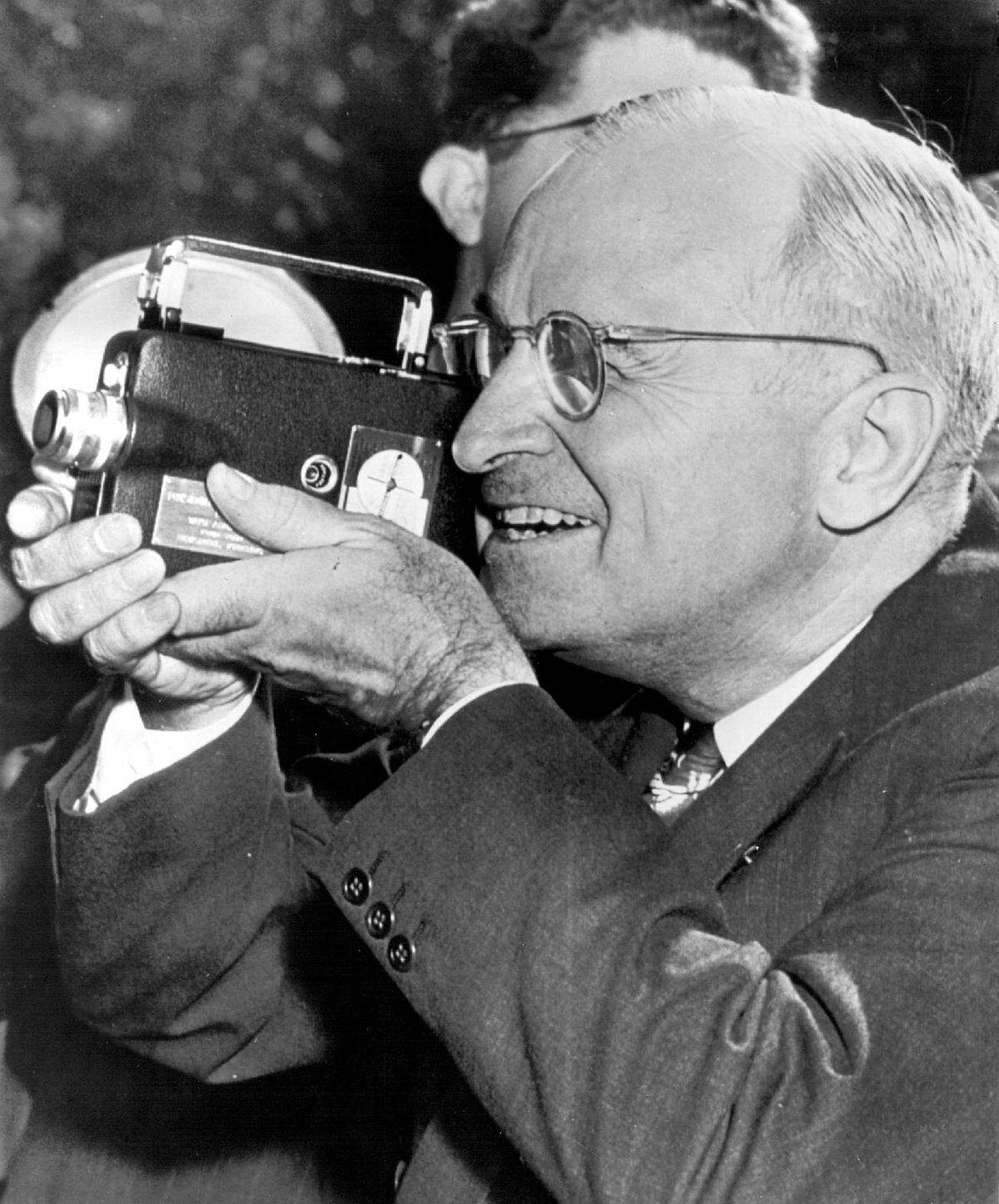 President Harry S. Truman operates a movie camera on the south lawn of the White House in 1947. Members of the White House News Photographers Association presented him with a movie and still camera during a brief ceremony.