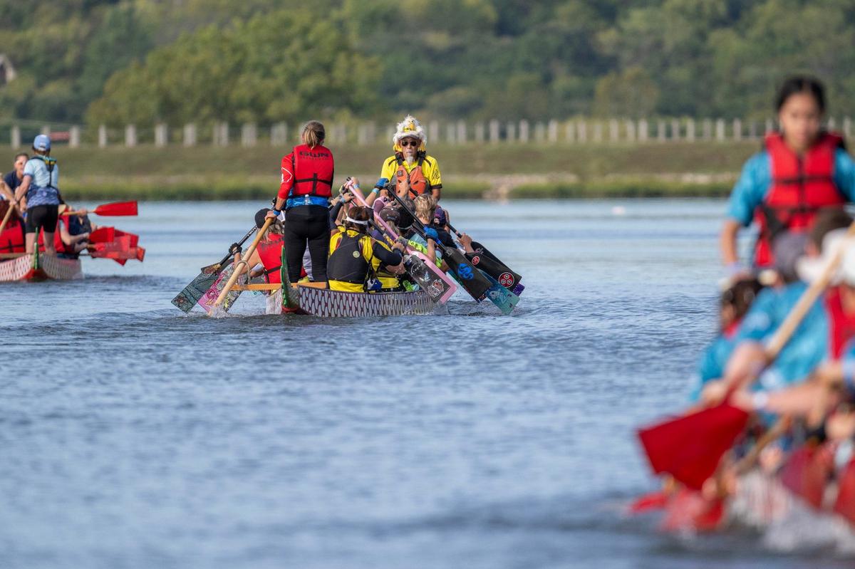 Crew members row to the starting line for a qualifying race during the KC Dragon Boat Festival on Saturday, Sept. 28, 2024, at Shawnee Mission Park.