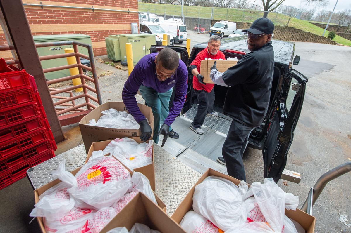 From left, Robert Hopkins, Alejandro Vasquez and Wendall Toombs load boxes of packaged lunches onto a van that would go to Lincoln Prep for safe storage and refrigeration. Families will come in to pick up sack meals next week.