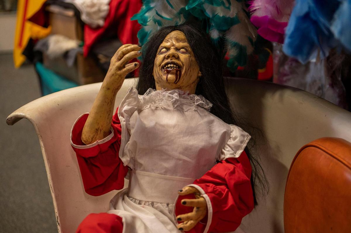 A gory plastic doll lounges on a chair inside Have Guns Will Rent Costumes and Props.