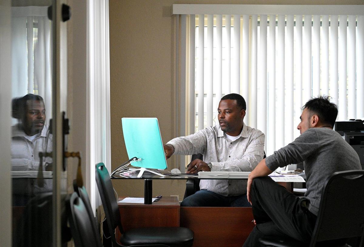 After Javier Martinez, right, looks at a few cars at Watson’s Auto Wholesale, owner Marcus Watson helps him find financing. Watson routinely helps customers find the best way to pay for their cars. When their credit rating rises, they can upgrade their car.