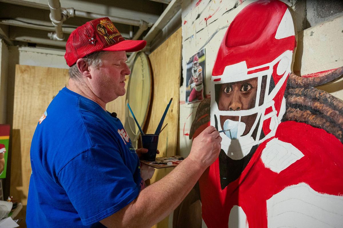 Jeff Parson paints an eye-catching likeness of Kansas City Chiefs wide running back Kareem Hunt on Wednesday in the basement studio of his Riverside home. The cutout will be added to the Chiefs display in his front yard on Gateway Drive in Riverside.