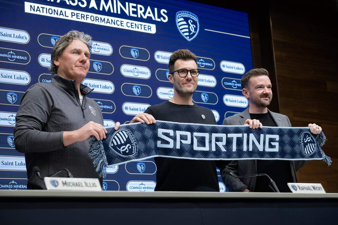 Sporting Kansas City co-principal owner Michael Illig, left, new head coach Raphael Wicky and president of soccer operations and general manager David Lee hold a scarf during an introductory press conference at the Compass Minerals National Performance Center on Tuesday, Jan. 6, 2026, in Kansas City, Kansas.