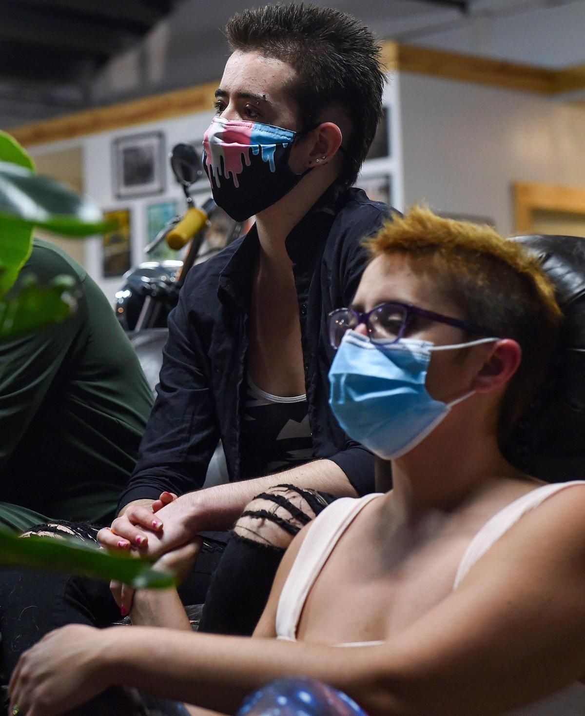 After performing an original poem at Blip Roasters in Kansas City’s West Bottoms, Zoe Dunning, left, listens to other poets with Mel Carabajal on Oct. 13. Dunning, who says they underwent conversion therapy, has become a vocal opponent of the practice.
