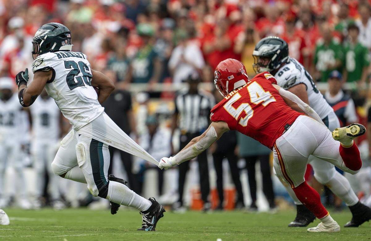 Philadelphia Eagles running back Saquon Barkley (26) carries the ball as Kansas City Chiefs linebacker Leo Chenal (54) has a hold of his undershirt at GEHA Field at Arrowhead Stadium on Sunday, Sept. 14, 2025, in Kansas City.