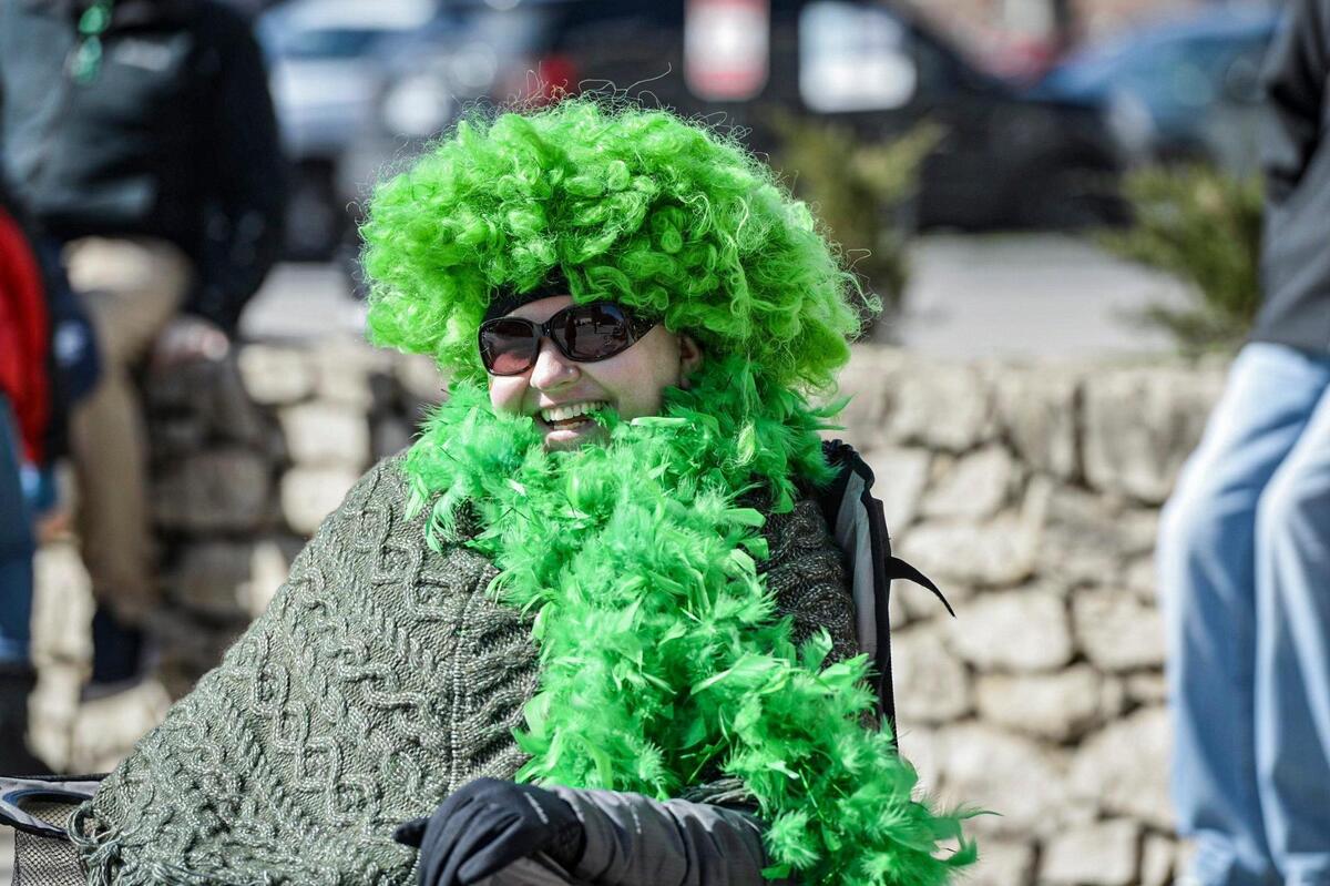 Tiffany Hayes kept warm under her green boa and wig Friday, March 17, 2023, during the annual St. Patrick’s Day parade in Kansas City.