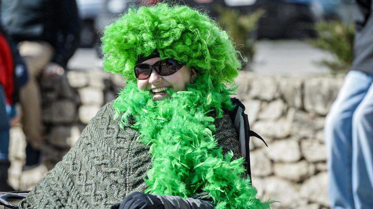 Tiffany Hayes kept warm under her green boa and wig Friday, March 17, 2023, during the annual St. Patrick’s Day parade in Kansas City.