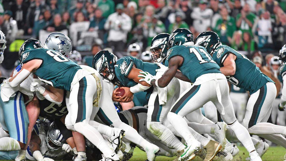 Philadelphia Eagles quarterback Jalen Hurts (1) picks up yardage a first down with a push from wide receiver A.J. Brown (11) and tight end Dallas Goedert (88) against the Dallas Cowboys at Lincoln Financial Field.
