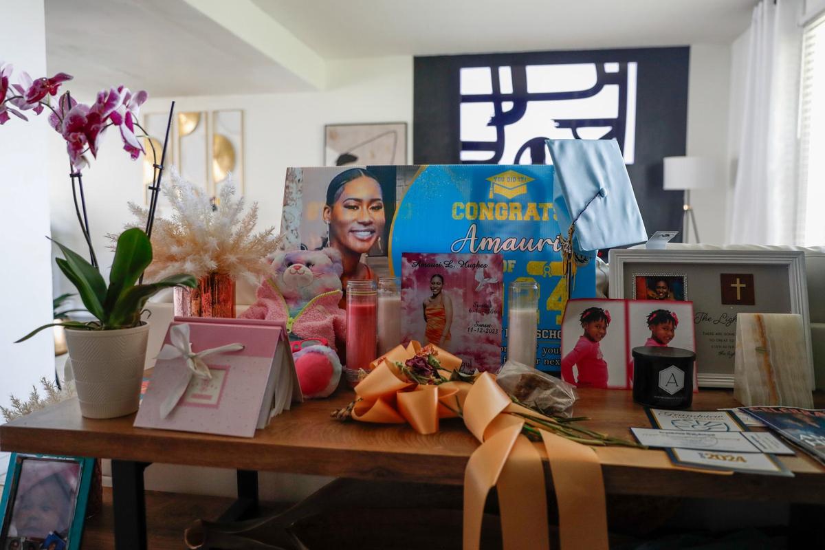 Flowers, photographs, a graduation cap and more cover an entry way table in Jenele Hughes’s home.