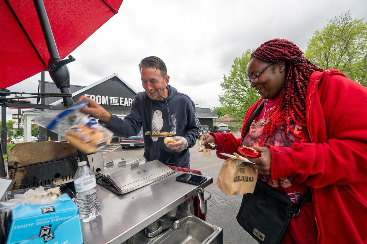 Naisha Kershaw of Kansas City purchases a hot dog, soda and a bag of chips from vendor Jason Vanderlinden after a stop at From the Earth dispensary. 