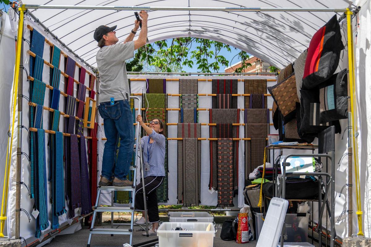 Richard Davidson, from Freedom, Wyoming, assists his partner Pamela Whitlock in assembling lights in their booth while preparing for the Brookside Art Annual.