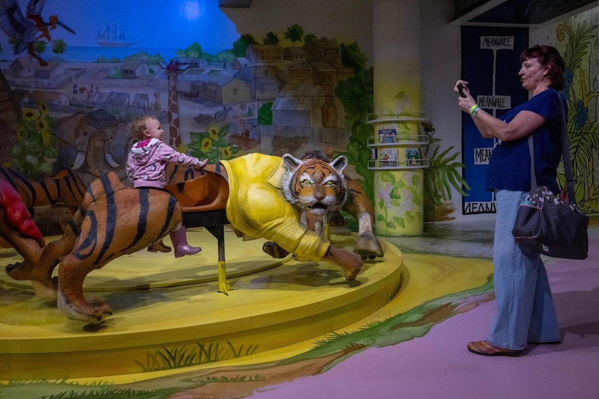 Lisa Lentes-Agee of Raytown snaps a photo of her granddaughter, Danni Agee, 2, at the Rabbit hOle’s “Sam and the Tigers” exhibit, designed as a carousel.