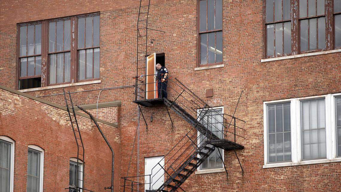 A police officer looks out the fire escape door that the offender used to gain access into a Chicago Police Department building in the Homan Square neighborhood of Chicago on Monday, Sept. 26, 2022.