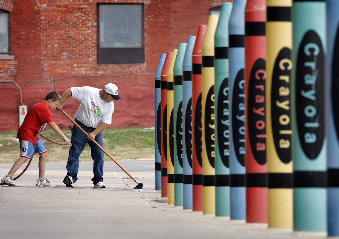 In this 2006 photo, a man and his stepson clean outside the Children’s Center Campus, 3101 Main St., where large crayon sculptures serve as a colorful barrier between the sidewalk and parking lot.