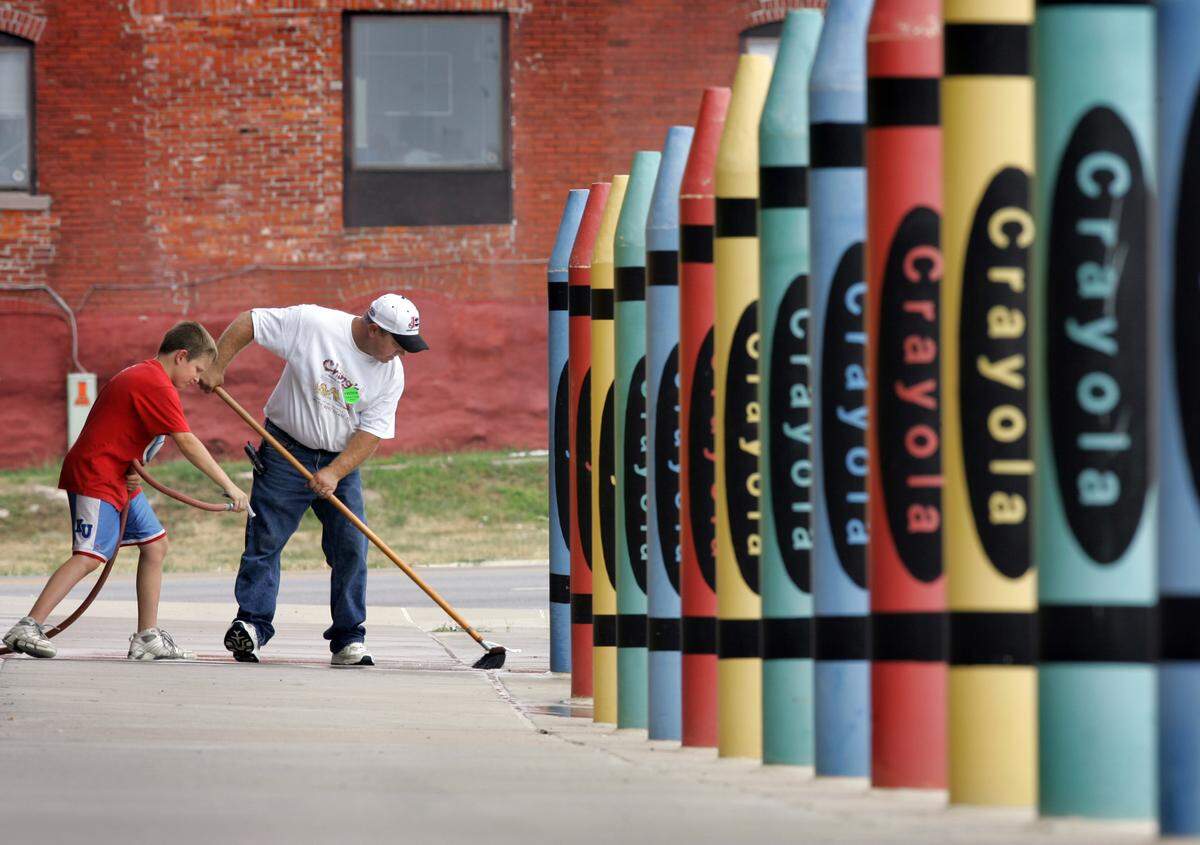 In this 2006 photo, Clark Waage and his stepson, Zach Bagwell, clean outside the Children’s Center Campus, 3101 Main St. Large crayon sculptures serve as a colorful barrier between the sidewalk and parking lot—a fitting symbol of Hallmark’s Kansas City roots and its connection to Crayola, creativity, and community.