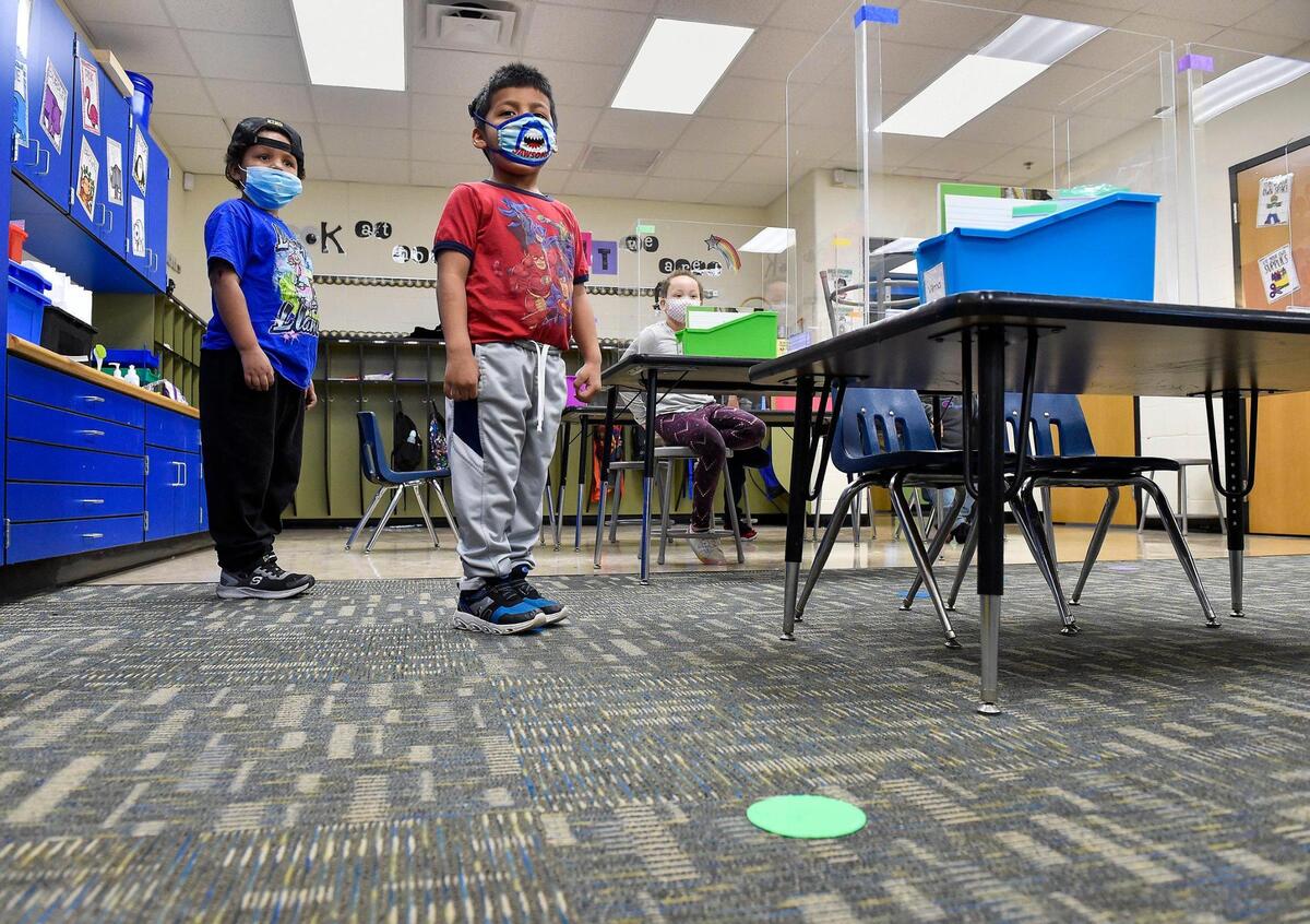 King White-Nelson, left, and Toby Chavez-Tello practice standing on green spots - their assigned color - on the floor. Reminders of the coronavirus were all around the school, including desk partitions and color-coded distancing spots on the floor in Marion Heck’s first grade class. Students arrived at Douglass Elementary School in Kansas City, Kansas, Wednesday, March 31, 2021, for the first day of full in-person learning. According to Principal Louis Neal, about 75 percent of students are coming back for in-person learning.