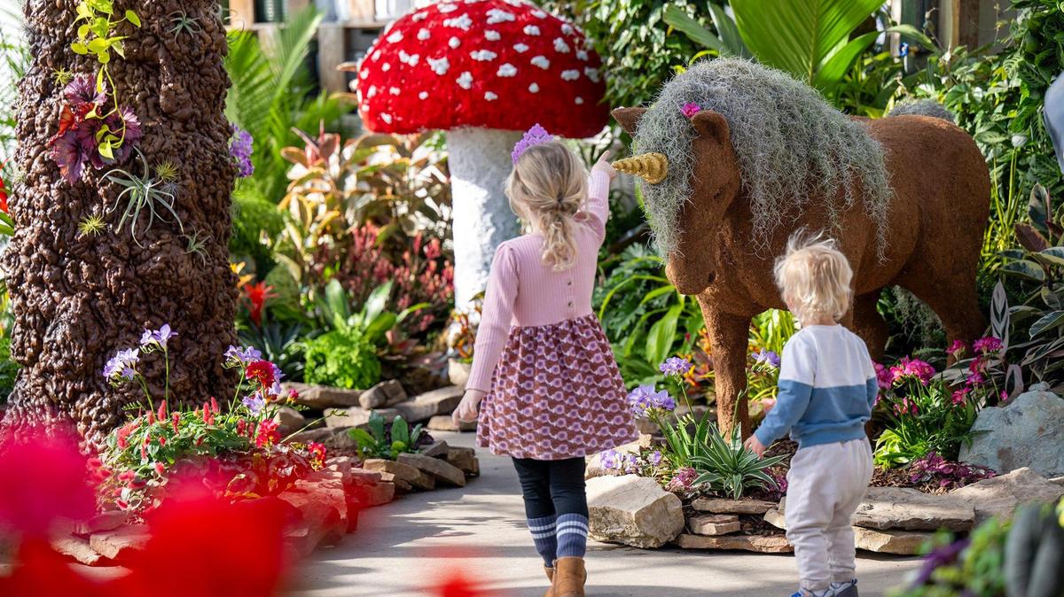 Mae Kellerman, 5, and her brother, Brooks Dudzinski, 2, of Overland Park, visit a whimsical garden display inside Shawnee’s greenhouse.