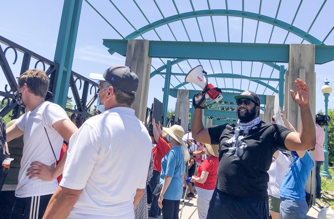 A group of about 60 protesters gathers Sunday, June 7, 2020, at a bridge on Meyer Boulevard over Highway 71. They stand in silence, some with their arms raised, for eight minutes and 46 seconds to honor George Floyd, who was killed by a Minneapolis police officer.
