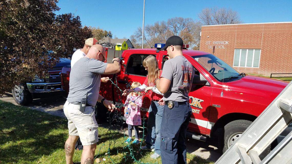 McCook Fire Department chief Marc Harpham, in the gray T-shirt, and other volunteers prepare lights to decorate the home of Kathy Hass, back.