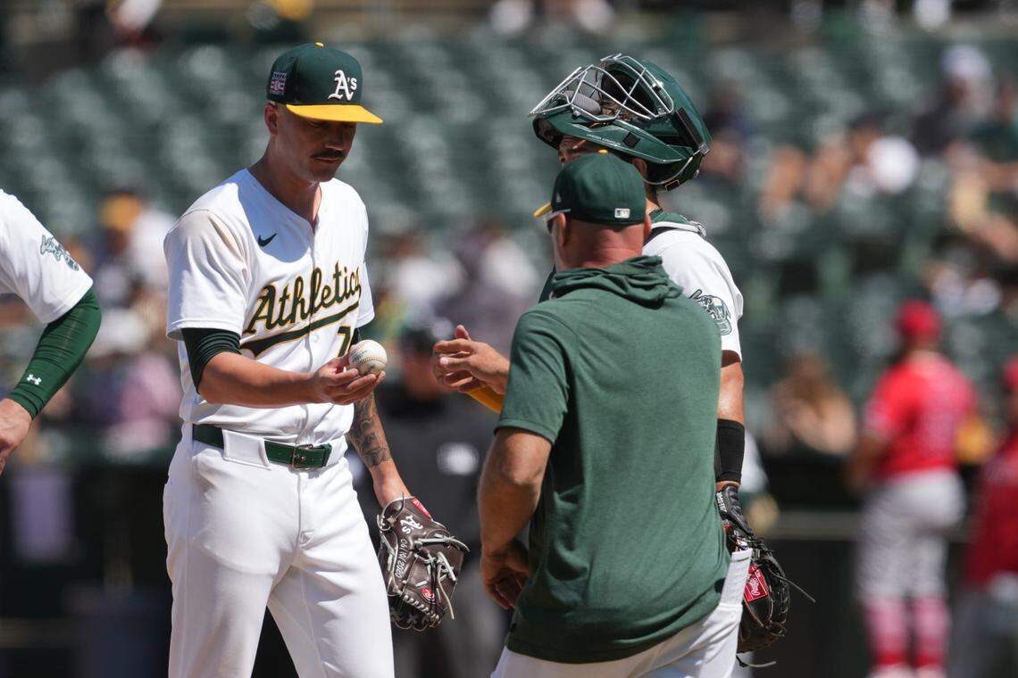 Then with the Oakland Athletics, relief pitcher Lucas Erceg (left) hands the ball to manager Mark Kotsay during a game against the Los Angeles Angels.