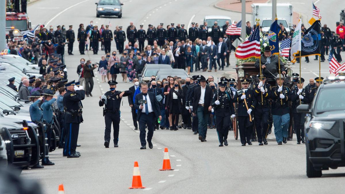 Law enforcement officers saluted as the horse-drawn hearse carrying the casket of slain Overland Park police officer Mike Mosher traveled along Metcalf Ave. on the way to the cemetery. Mosher was killed in the line of duty on May 3.