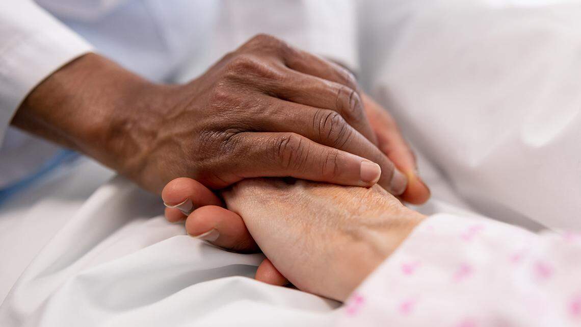 Close-up on a doctor holding the hand of a sick woman in bed at the hospital - healthcare and medicine health careHispanolistic