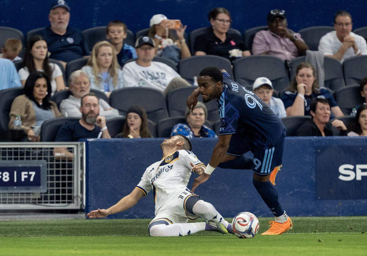 LA Galaxy midfielder Gabriel Pec (11) goes down after hitting Sporting Kansas City defender Jayden Reid (99) in the first half at Sporting Park on Wednesday, May 13, 2026, 2026, in Kansas City, Kansas,