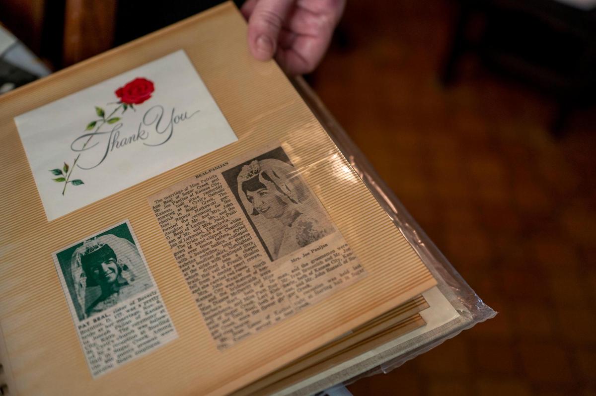 Gina Dorough, youngest daughter of Patrica “Pat” Panijan, shows a newspaper clipping that her mother saved in a photo album from when her parents were married in Kansas City, Kan. on Tuesday, Dec 28, 2021.