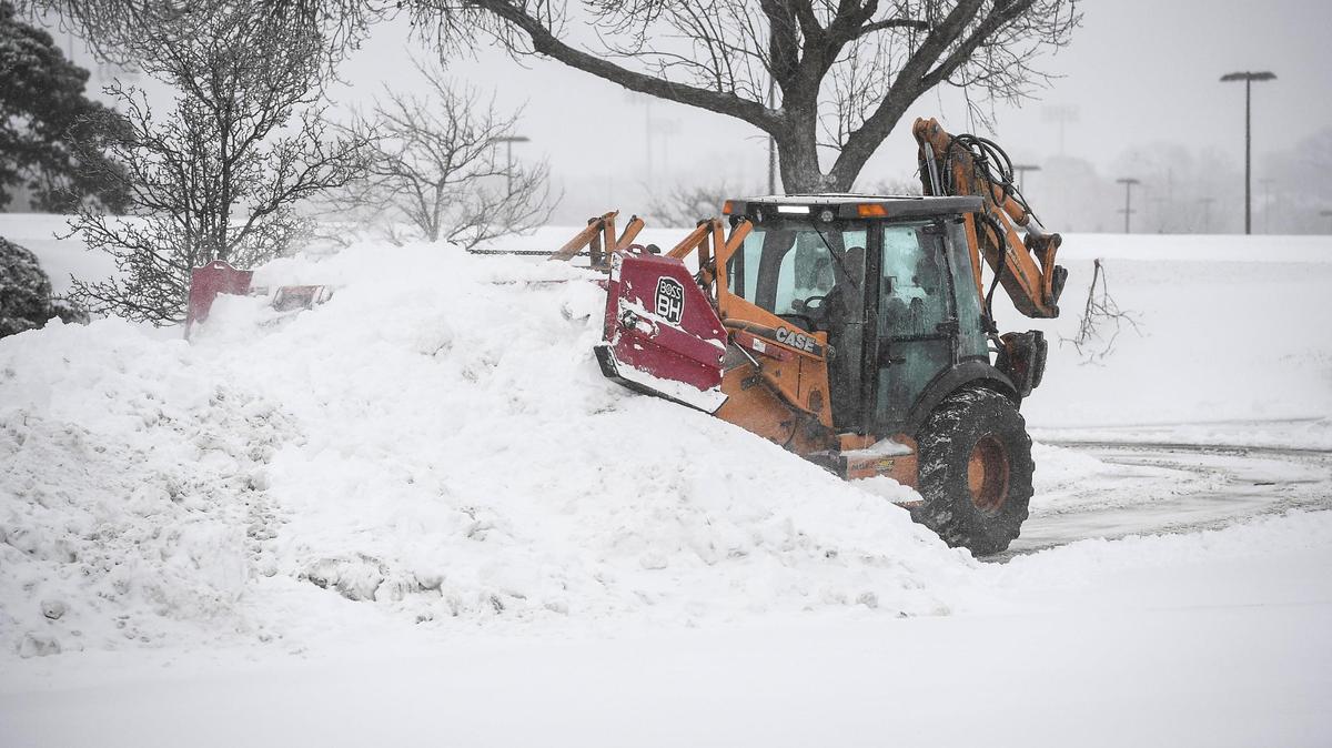 A tractor clears the parking lot of snow Sunday, Jan. 5, 2025, at Orchard Corners shopping center in Lenexa.
