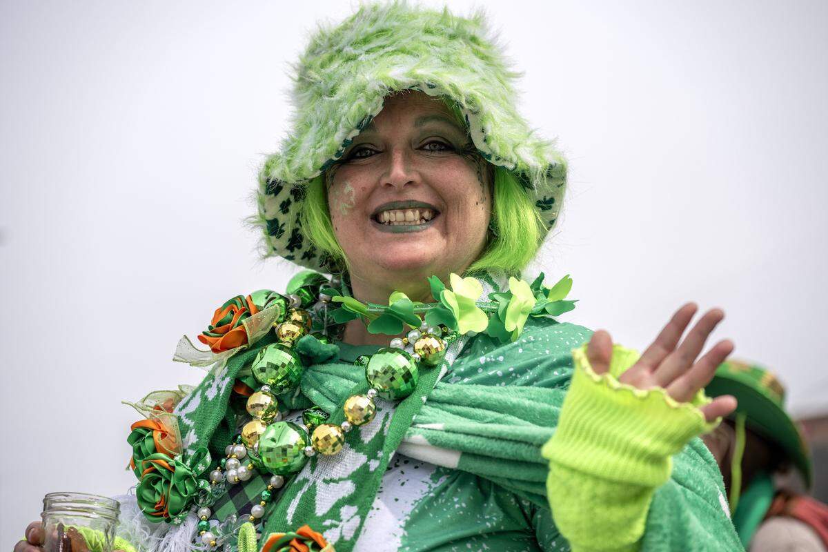April Coleman waves and smiles as she is in a head-to-toe green attire while attending the St. Patrick's Day parade on Tuesday, March 17, 2026, in Kansas City.