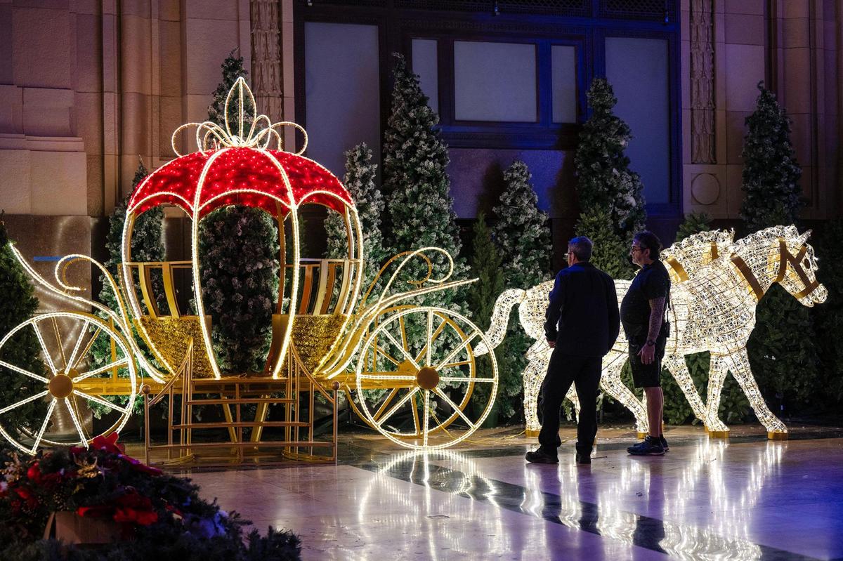 Workers look over a lighted, full-size horse drawn carriage display during set up of Holiday Reflections in Union Station’s Grand Plaza.