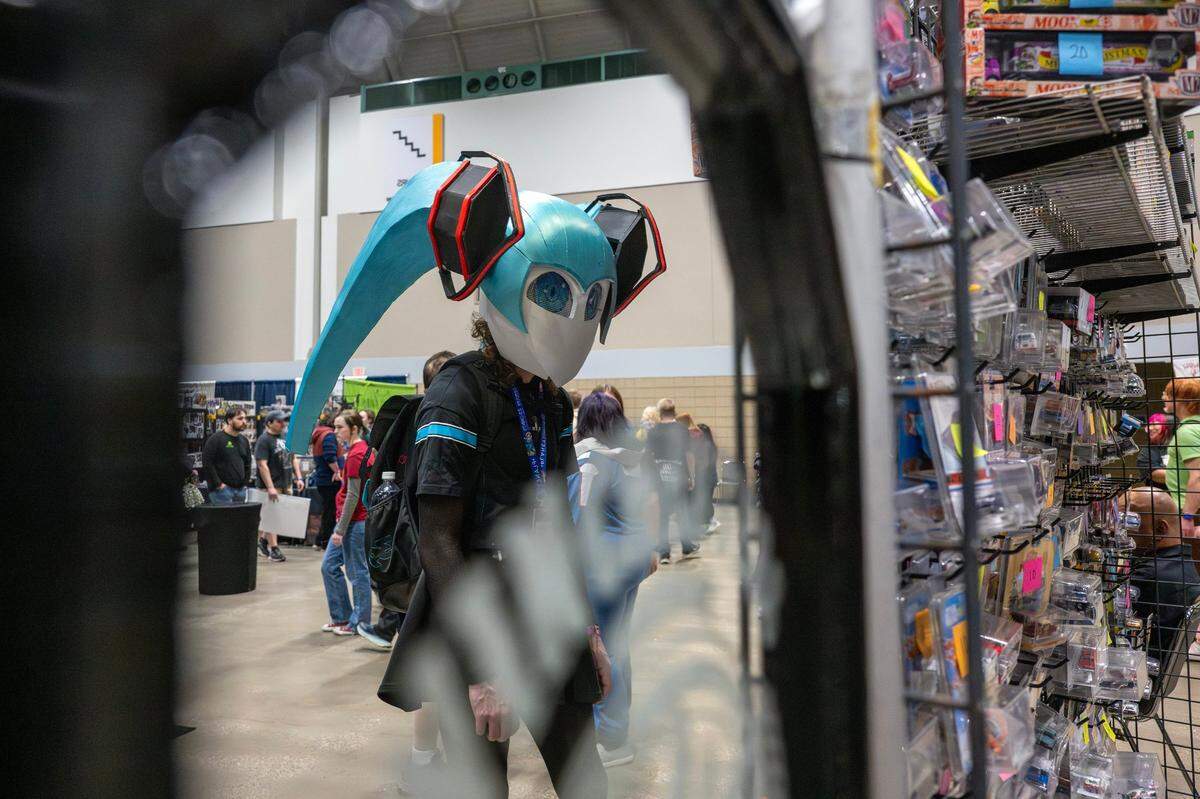 Kyle Etter, cosplaying as a mecha version of the anime character Mico, looks at merchandise while attending Planet Comicon at the Kansas City Convention Center on Friday, March 21, 2025.