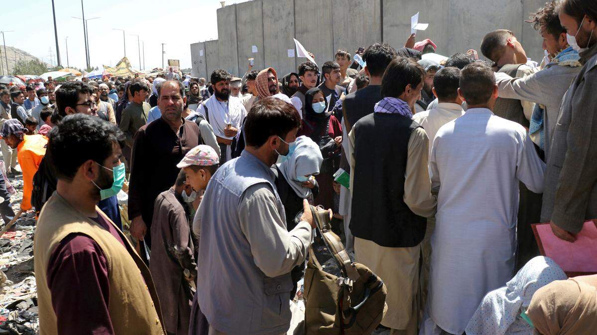 Hundreds of people, some holding documents, gather near an evacuation control checkpoint on the perimeter of the Hamid Karzai International Airport, in Kabul, Afghanistan, Thursday, Aug. 26, 2021.