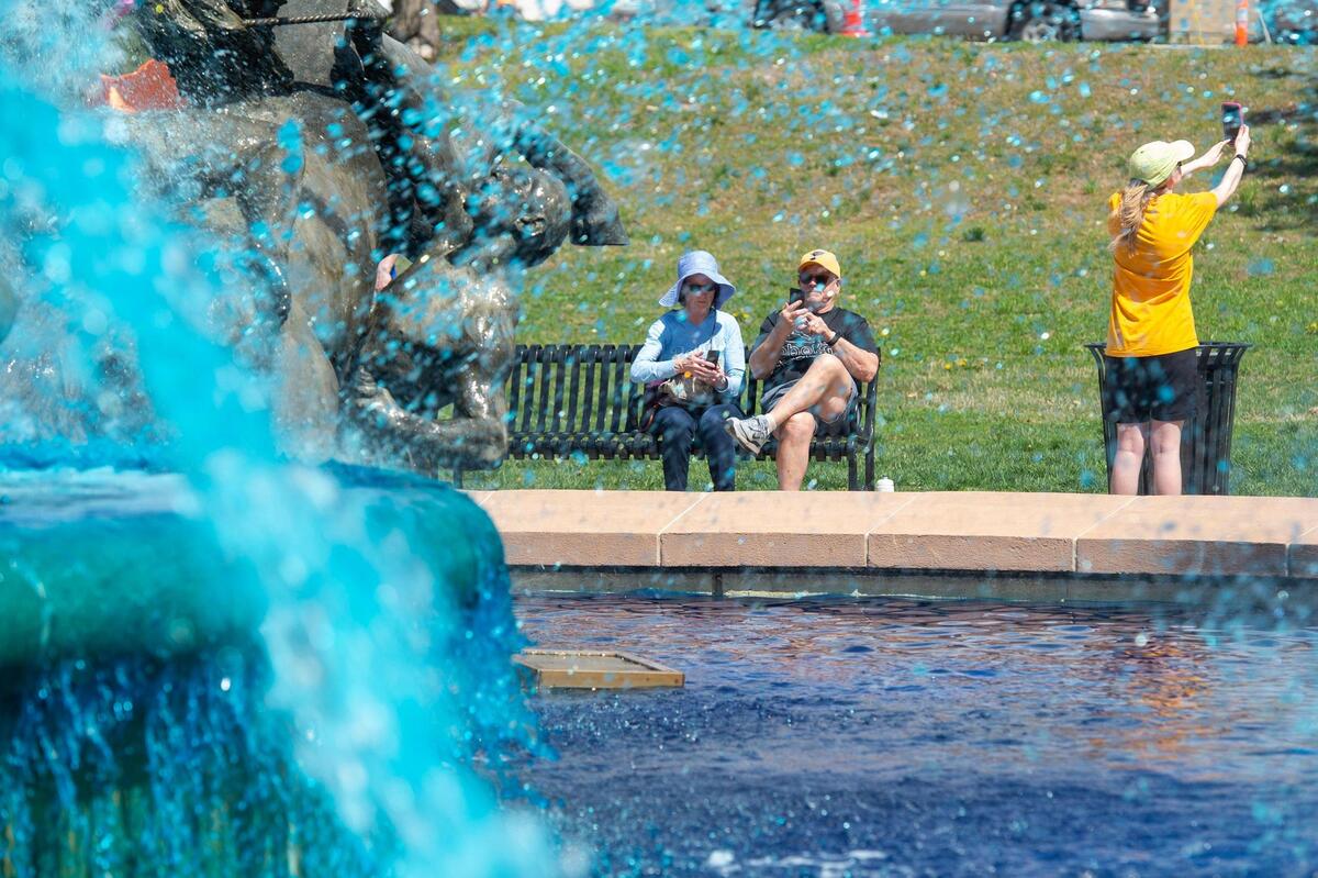 Visitors attend the opening celebration of Fountain Day at Mill Creek Park in 2023. The Mill Creek fountain was dyed blue to celebrate the Kansas City Royals. There are 48 publicly owned fountains in Kansas City.