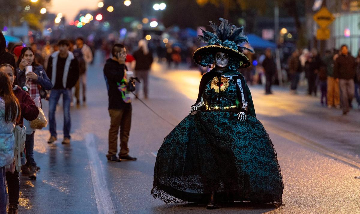 Corinna Mejía-Ridenour walks along Central Avenue during the Día de los Muertos parade hosted by the Central Avenue Betterment Association on Saturday in Kansas City, Kan.