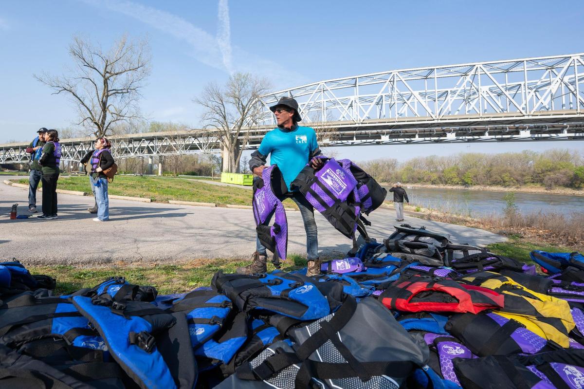 A volunteer hands out life jackets to people attending a cleanup event held by Missouri River Relief on April 12, 2025. Volunteers rode boats down the river to various locations along the banks to clean up litter and trash.