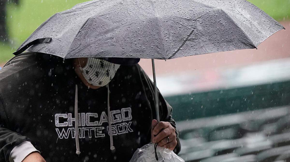 A baseball fan holds an umbrella against rain during a rain delay before a baseball game between the Kansas City Royals and theChicago White Sox in Chicago, Thursday, April 8, 2021. (AP Photo/Nam Y. Huh)