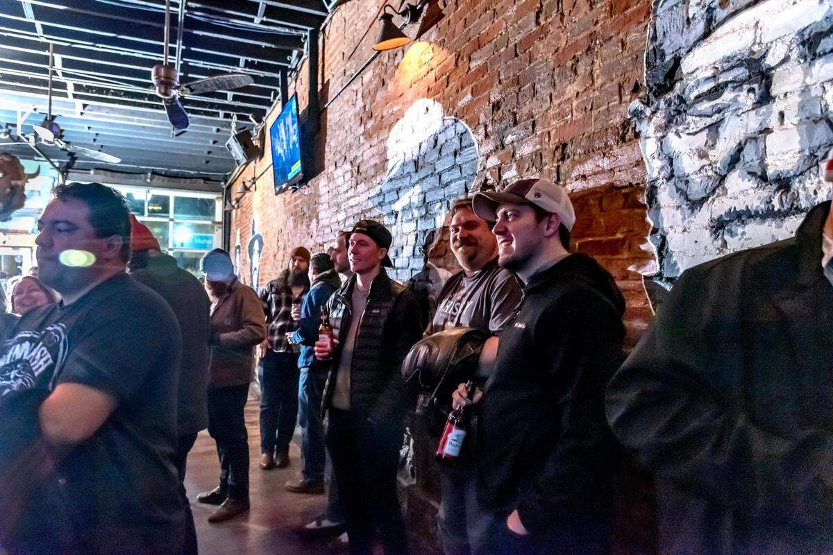 Customers listen to a band with a backdrop of images of Willie Nelson and other country musicians adorning the brick walls of the Westport Saloon.