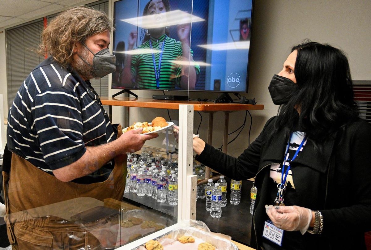 Letitia Ferwalt hands David Thayer a meal. Thayer is unhoused but said he sought shelter due to frigid temperatures. Volunteers conducted an annual point-in-time survey of people experiencing homelessness at Project 10-20 in Lenexa, Tuesday night, Jan. 25, 2022. Temperatures dropped into the low teens that night.