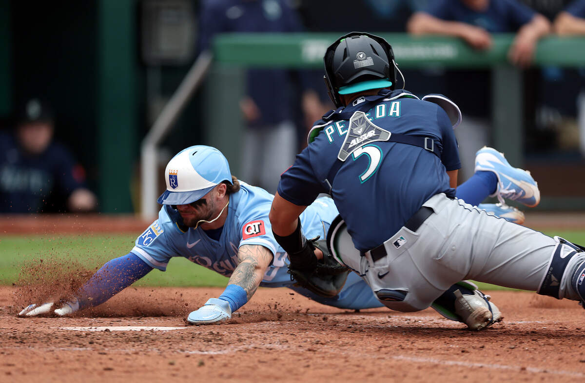 Carter Jensen #22 of the Kansas City Royals slides safely into home plate to score past the tag of Jhonny Pereda #5 of the Seattle Mariners during the 6th inning of the game at Kauffman Stadium on May 23, 2026 in Kansas City, Missouri.