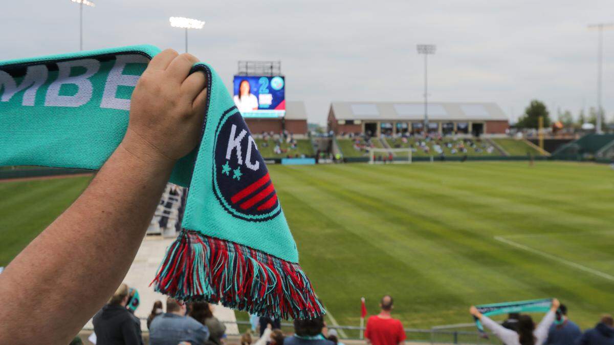 A KC NWSL fan holds aloft a scarf during player introductions before the team’s first home match (against OL Reign) at Legends Field in Kansas City, Kan.