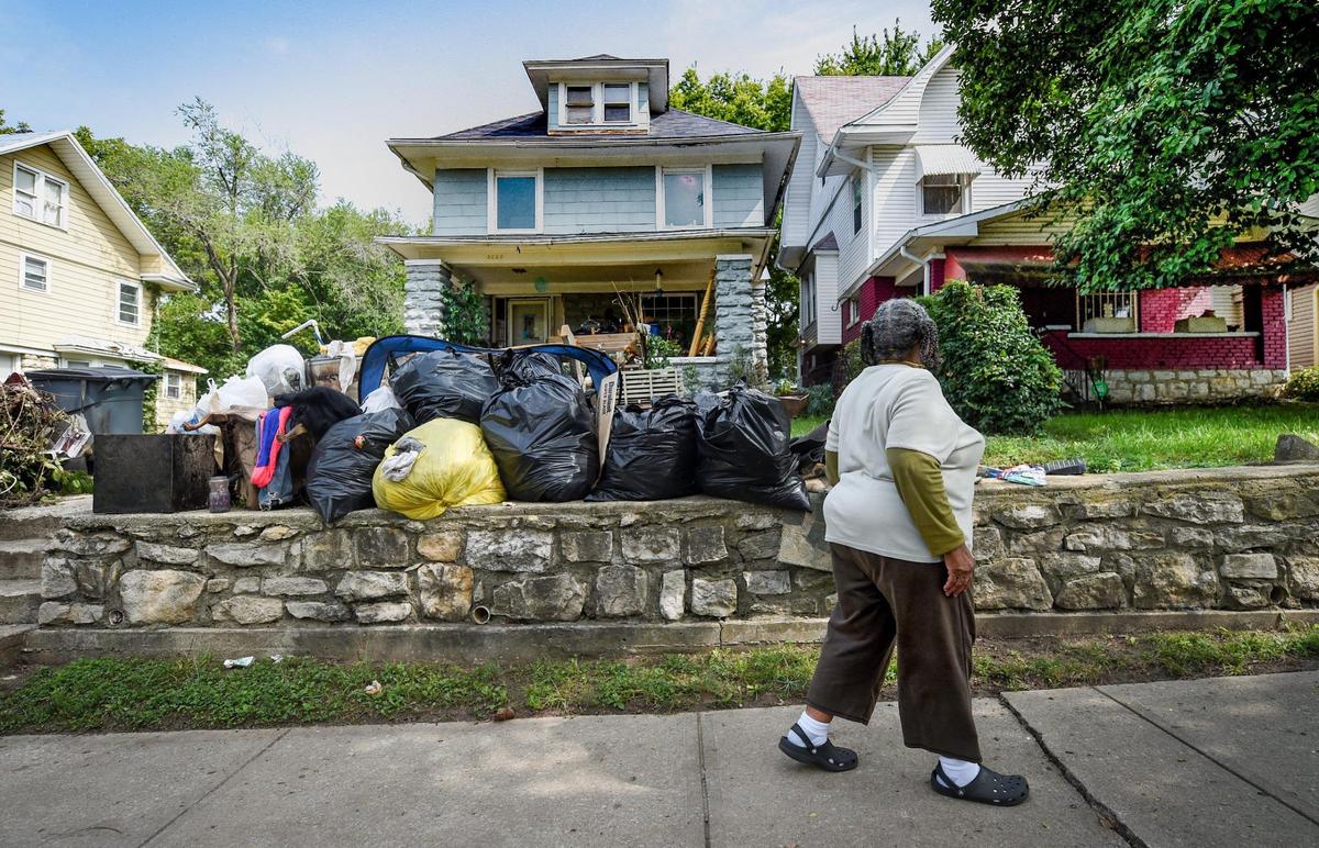 Barbara J.K. Johnson, 75, a retired teacher and professor, strolls along the sidewalk on South Benton Avenue where she lives and views a neighboring house with a yard filled with bags of trash and debris.