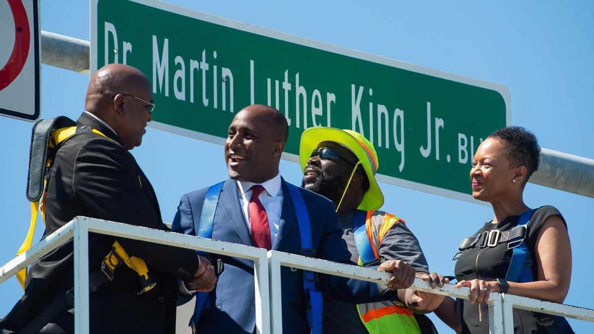 Kansas City Mayor Quinton Lucas shakes hands with Rev. Dr. Vernon Howard, along with Public Works employee Keon Ford and assistant city manager Kimiko Black Gilmore, in front of the newly-installed Dr Martin Luther King Jr. Boulevard sign at the intersection of The Paseo and the new MLK boulevard on Saturday, June 5, 2021.